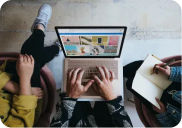 Three people smiling around a laptop